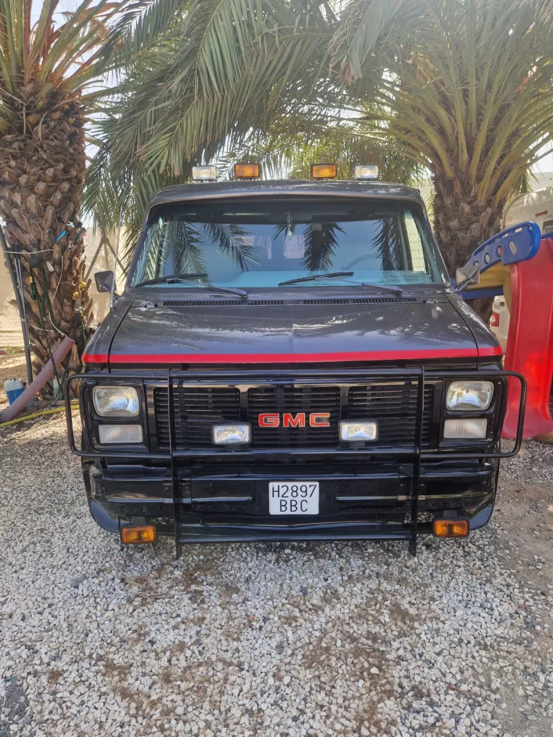 Front of the van with the red GMC grille, the bull bar and the roof spotlights