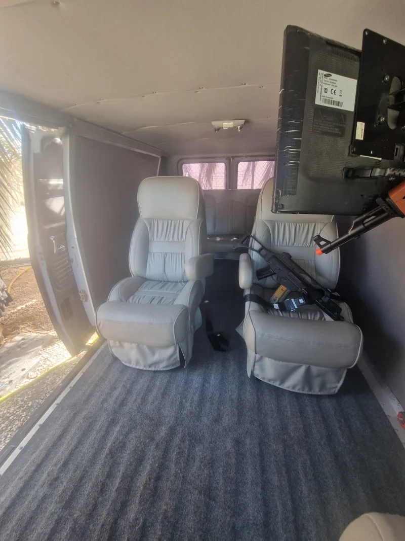 Rear interior of the van with captain's chairs, carpet and a TV