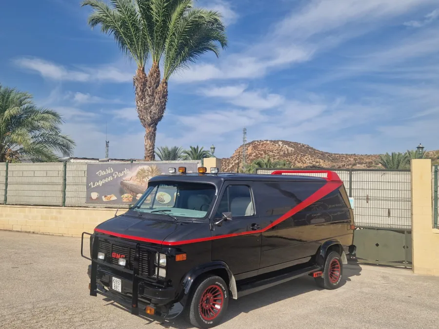 Side view of the black A-Team van with its red stripe parked in the sun